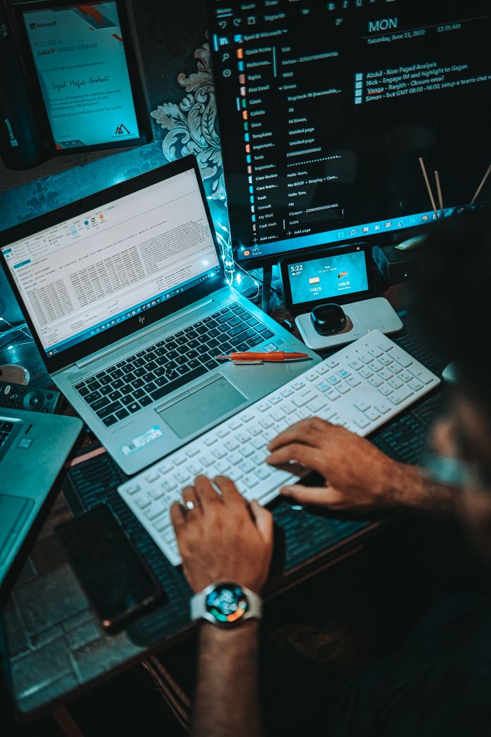 Crafting Captivating Headlines: Your awesome post title goes here A person working on a dual-monitor setup with a laptop and keyboard in an office environment.